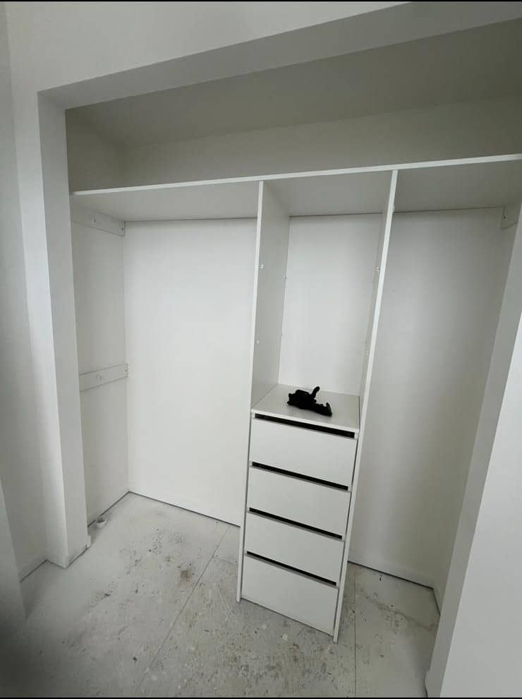 Expert installers fitting a built-in wardrobe in a client's bedroom.